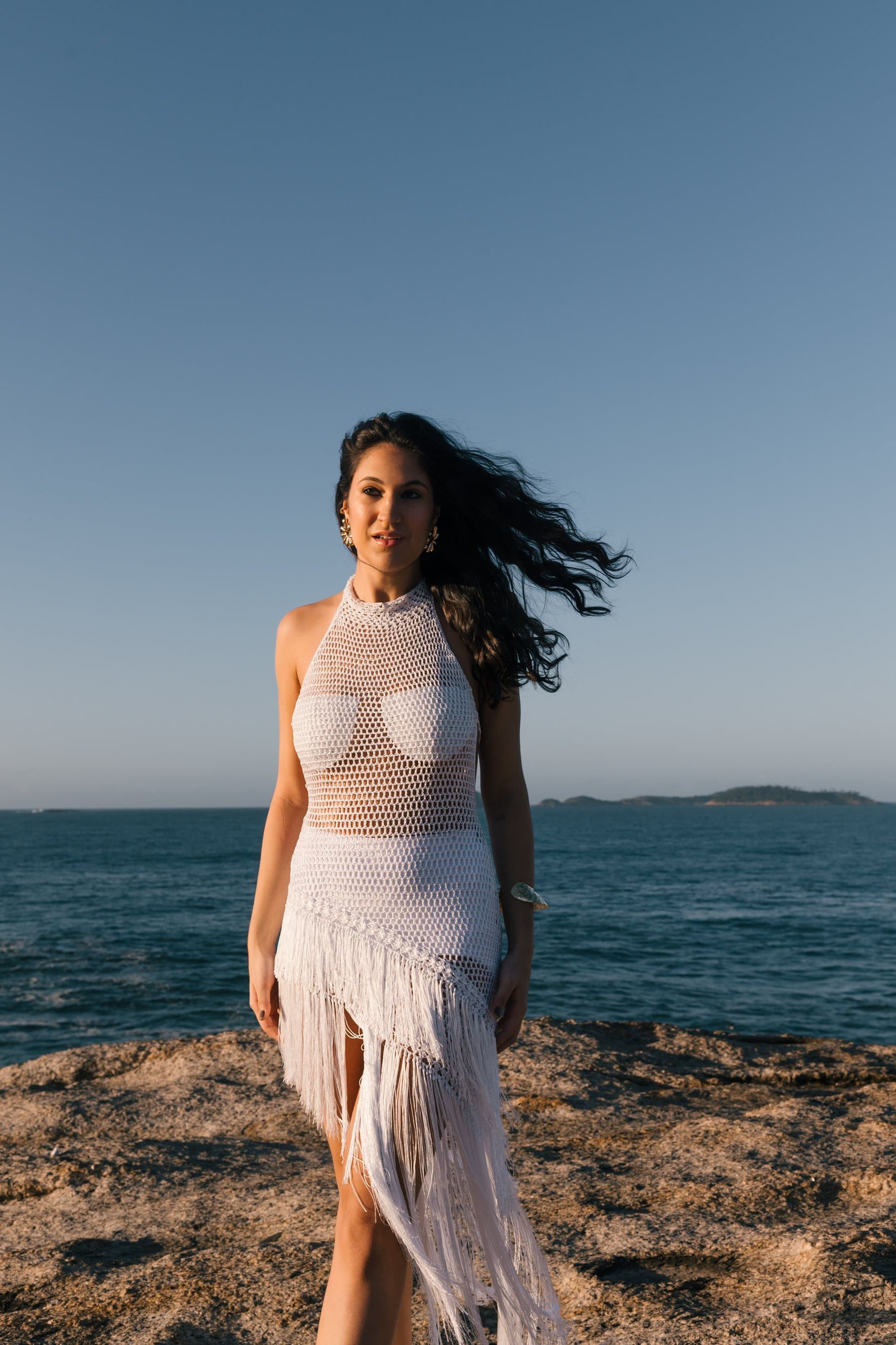 Vestido Riva em crochê Branco, longo, de gola alta e fenda, sobre a pedra